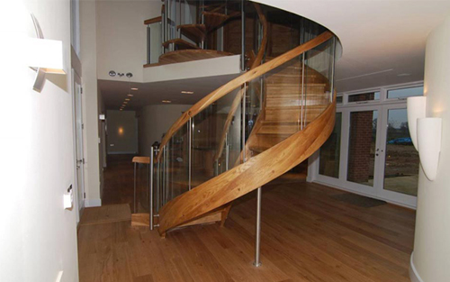 A wood and glass modern winding staircase in a home.