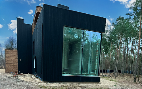 Modern home in the woods with floor to ceiling glass windows.